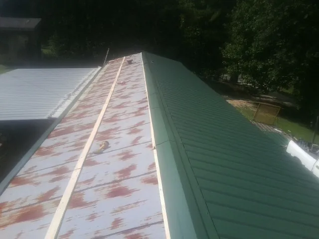 Old rusted panels beside newly installed green metal roofing — Wind Damage Roof Repair by Roofing Brothers in Orwigsburg