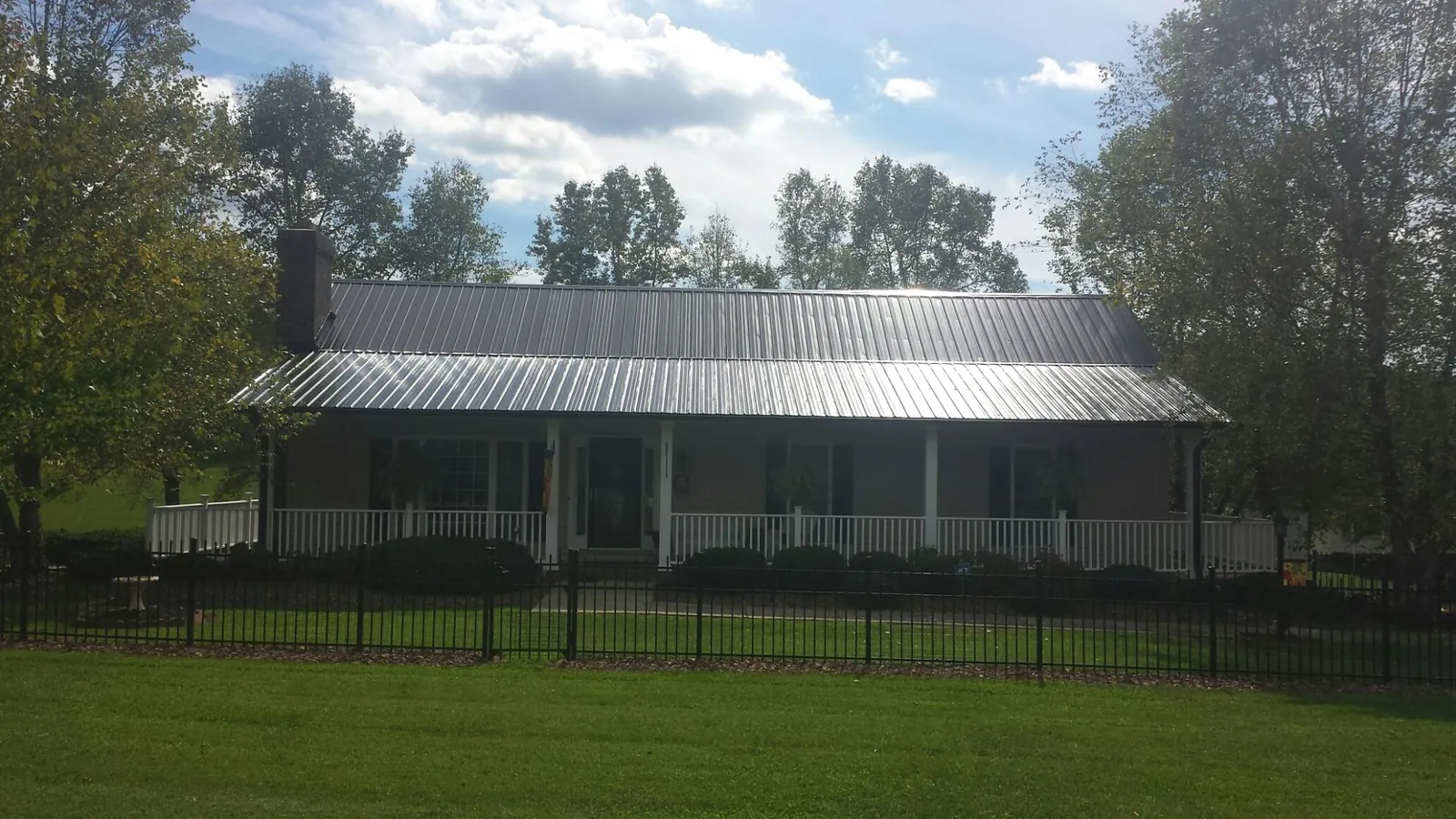 Gray metal roof on a brick ranch with a full width front porch — Gutter Guard Installation work by our crew in Orwigsburg