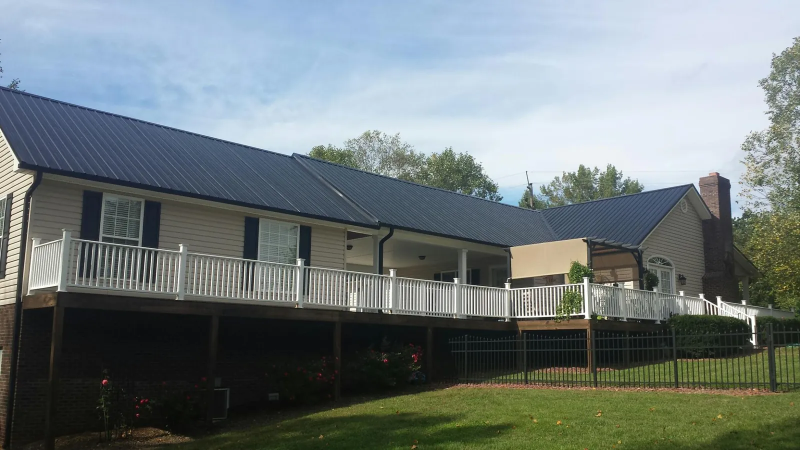 Black metal roof above a long white railed deck on a hillside home in Orwigsburg