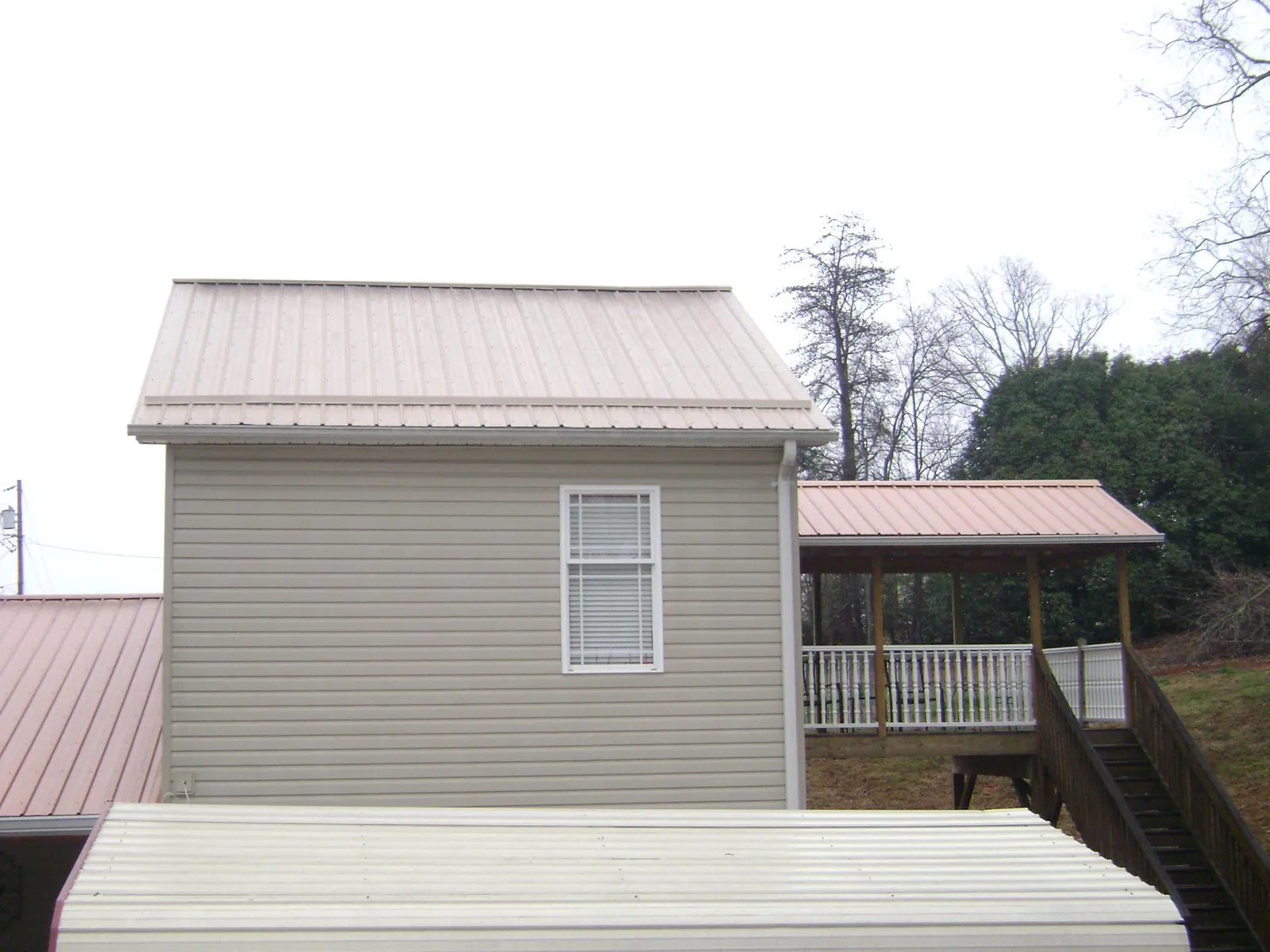 Tan metal roofs on a two story addition and attached porch, from a Roof Replacement job in Orwigsburg