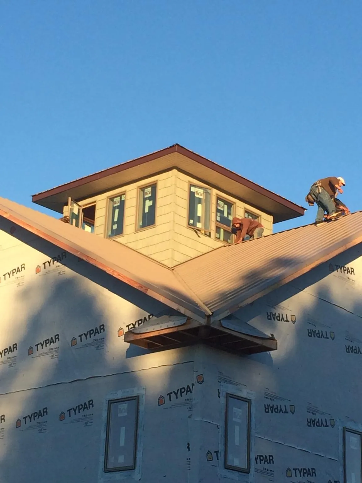 Roofers working around a rooftop cupola on a new metal roof at sunset — Roof Waterproofing in Orwigsburg by Roofing Brothers